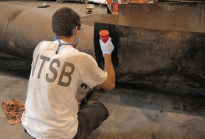 NTSB investigator examining fracture surfaces.